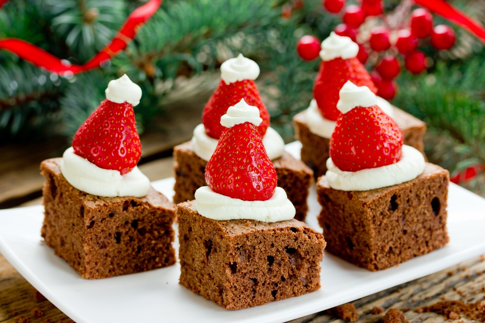 brownies with cream cheese frosting and strawberries to look like a santa hat